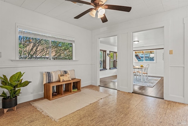 living area with a ceiling fan and baseboards