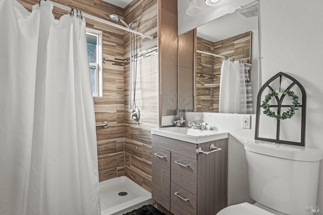 full bath featuring toilet, a tile shower, and vanity