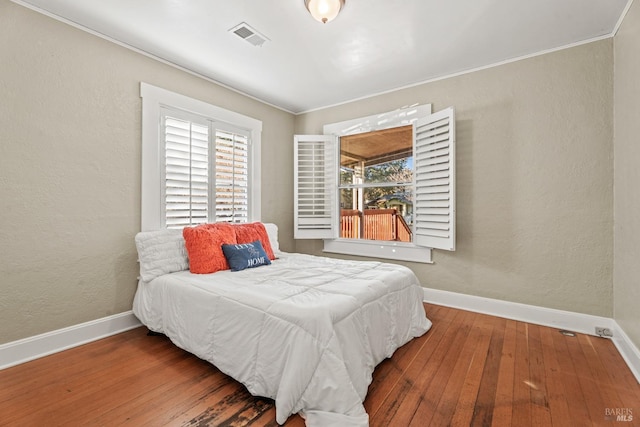 bedroom featuring hardwood / wood-style floors, visible vents, and baseboards