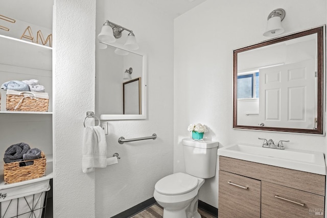 bathroom featuring toilet, baseboards, wood finished floors, and vanity