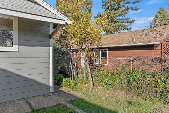 view of home's exterior featuring roof with shingles and fence