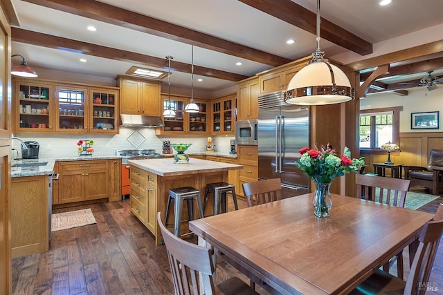 kitchen with a center island, sink, dark hardwood / wood-style floors, built in appliances, and pendant lighting