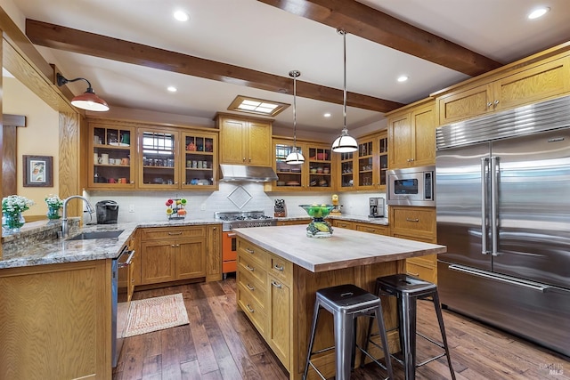 kitchen featuring backsplash, dark wood-type flooring, built in appliances, beam ceiling, and a kitchen island