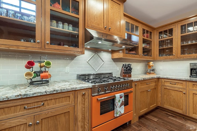 kitchen with dark hardwood / wood-style flooring, range with two ovens, light stone counters, and backsplash