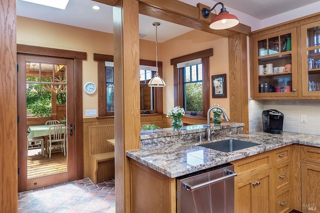 kitchen with dishwasher, light stone counters, hanging light fixtures, and sink