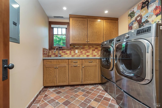 clothes washing area featuring electric panel, cabinets, sink, and washing machine and dryer