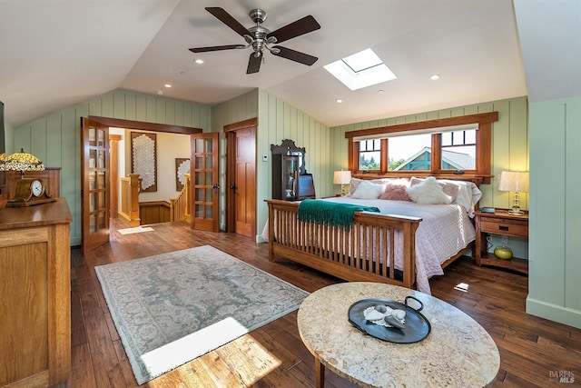 bedroom with ceiling fan, vaulted ceiling with skylight, wood walls, and dark hardwood / wood-style floors