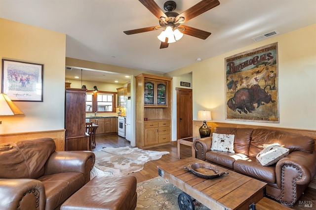 living room featuring light hardwood / wood-style flooring, ceiling fan, and sink