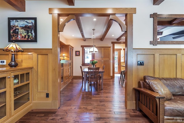 dining space with beamed ceiling, dark hardwood / wood-style floors, and wood walls