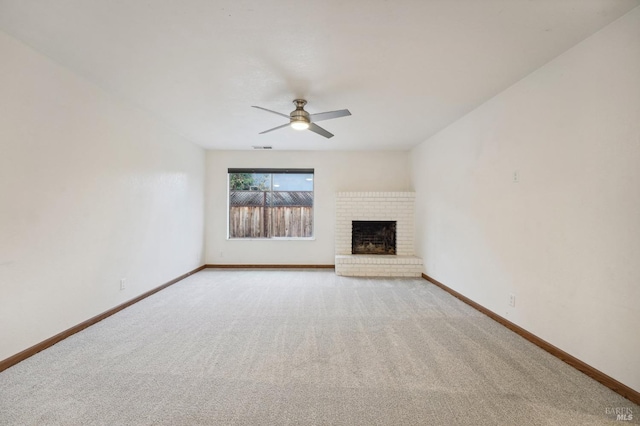 unfurnished living room with light colored carpet, a brick fireplace, and ceiling fan