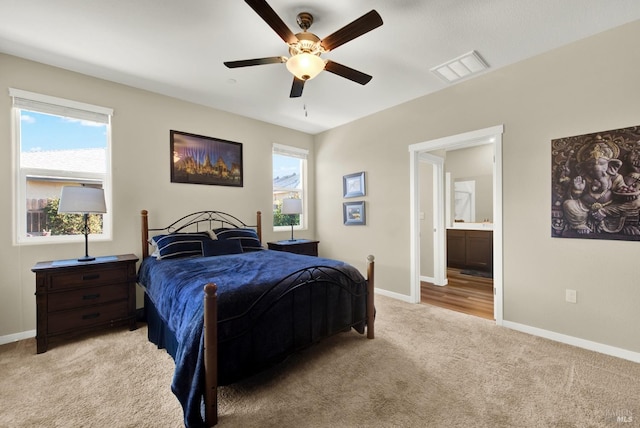 carpeted bedroom with connected bathroom, ceiling fan, and multiple windows