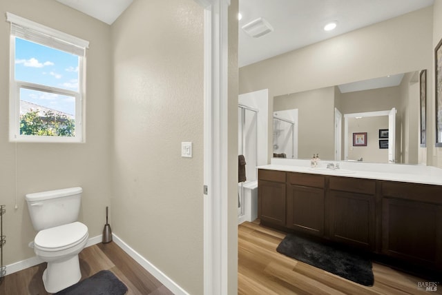 bathroom featuring hardwood / wood-style floors, vanity, toilet, and a shower with door