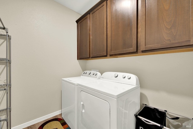 laundry area featuring separate washer and dryer, cabinets, and wood-type flooring