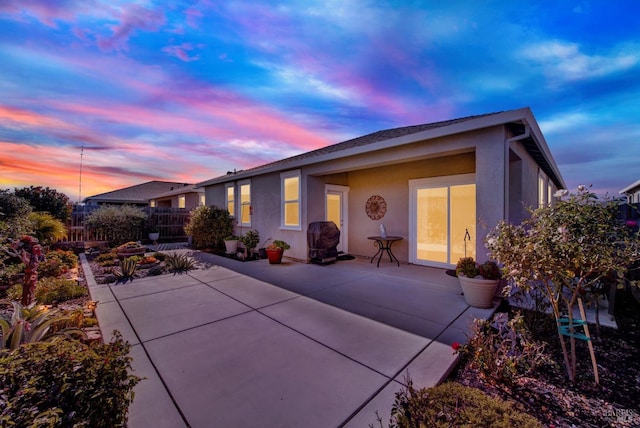 back house at dusk featuring a patio area