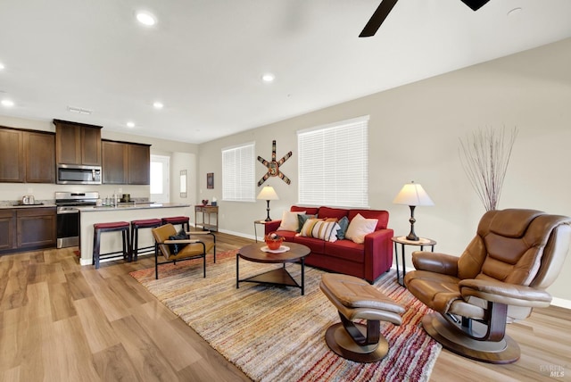 living room featuring ceiling fan and light hardwood / wood-style floors