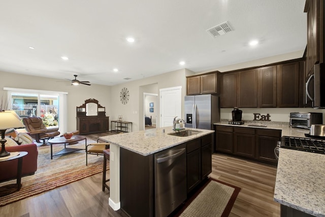 kitchen featuring appliances with stainless steel finishes, ceiling fan, dark wood-type flooring, sink, and an island with sink