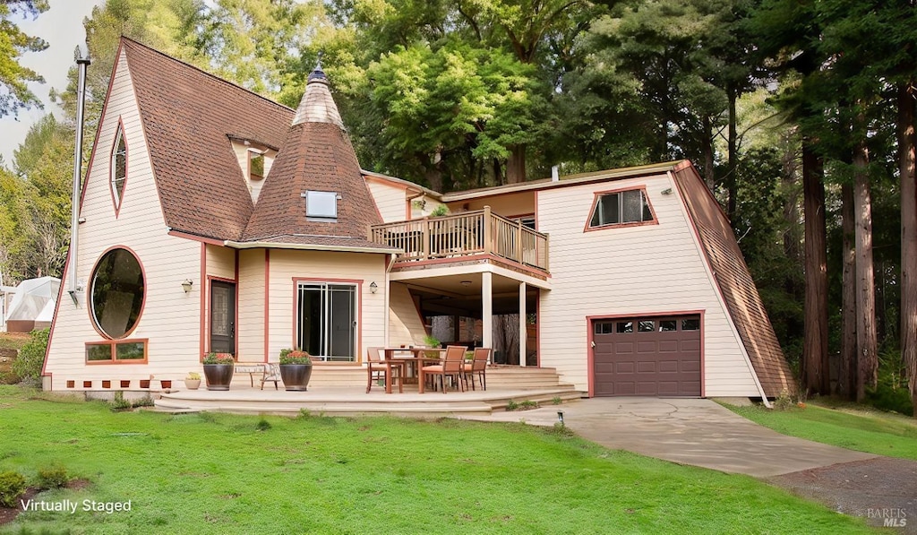 back of house with a garage, a balcony, and a yard