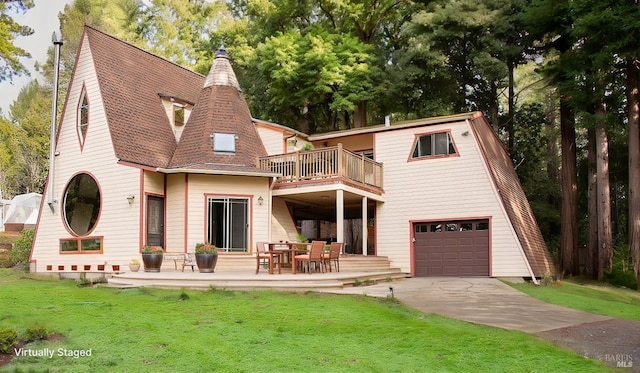 back of house with a garage, a balcony, and a yard