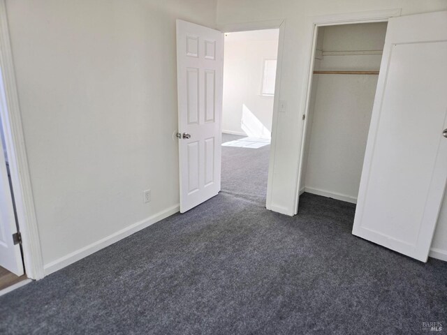 unfurnished bedroom with a closet and dark carpet