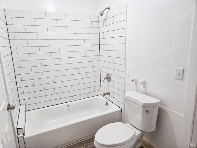 bathroom featuring tiled shower / bath combo, toilet, and wood-type flooring