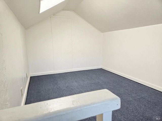 bonus room with vaulted ceiling with skylight and carpet