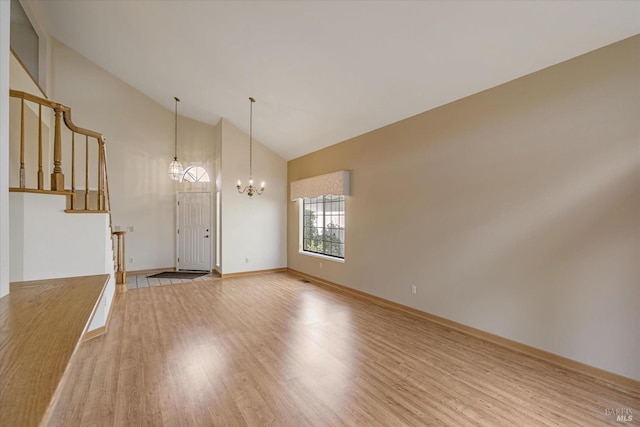 interior space with high vaulted ceiling, light wood-type flooring, and a notable chandelier