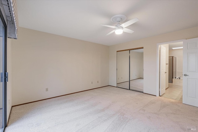 unfurnished bedroom featuring ceiling fan, a closet, ensuite bathroom, and light colored carpet