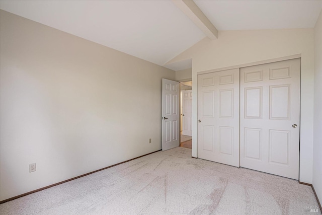 unfurnished bedroom with lofted ceiling with beams, a closet, and light colored carpet