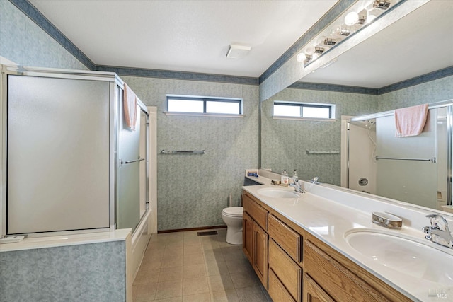 full bathroom featuring tile patterned flooring, vanity, combined bath / shower with glass door, and toilet