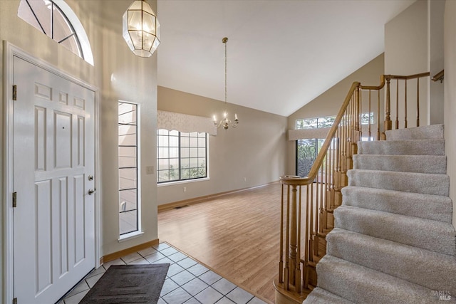 entryway with light tile patterned floors, high vaulted ceiling, and an inviting chandelier