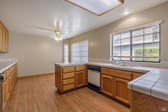 kitchen with sink, kitchen peninsula, tile countertops, white dishwasher, and light hardwood / wood-style floors