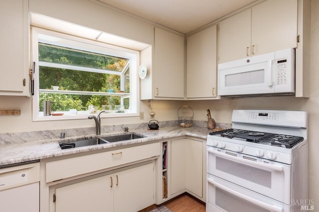 kitchen featuring light stone counters, white appliances, sink, light hardwood / wood-style floors, and white cabinetry