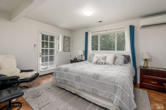 bedroom featuring a wall mounted air conditioner, beam ceiling, and hardwood / wood-style flooring