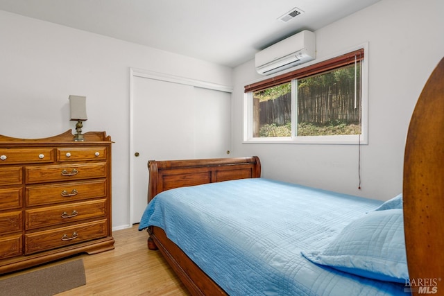 bedroom featuring a wall mounted AC, a closet, and light wood-type flooring