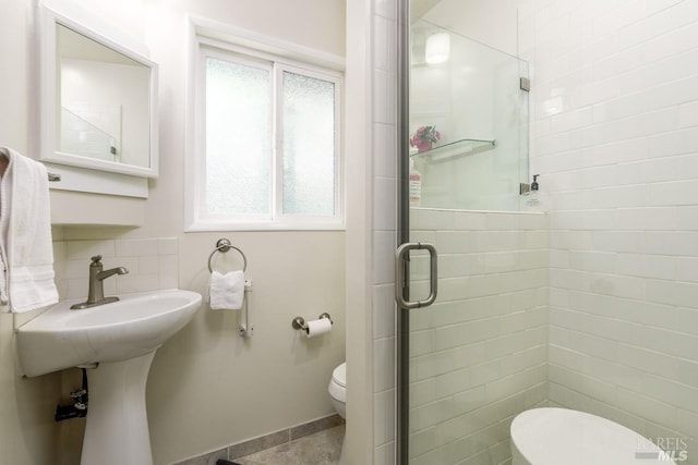 bathroom featuring toilet and a shower with shower door