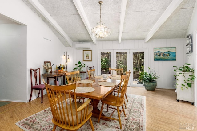 dining area with an inviting chandelier, french doors, light hardwood / wood-style flooring, a wall mounted AC, and beam ceiling