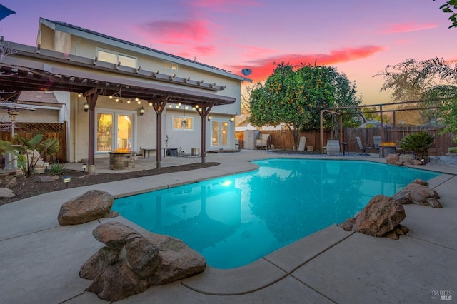 pool at dusk with a patio area