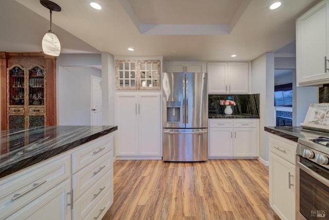 kitchen with backsplash, white cabinets, light hardwood / wood-style flooring, a tray ceiling, and stainless steel appliances