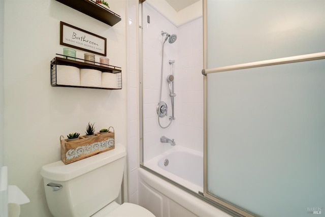 bathroom featuring toilet and shower / bath combination with glass door