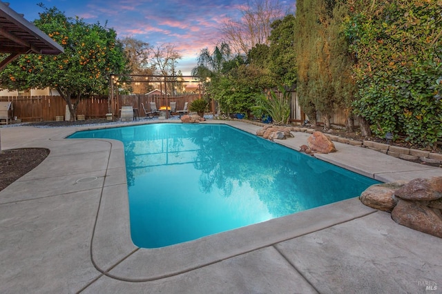 pool at dusk with a patio area