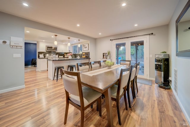 dining space with french doors and light wood-type flooring