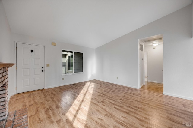 entryway with a fireplace, vaulted ceiling, and light hardwood / wood-style flooring