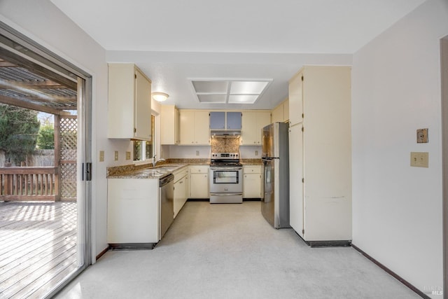 kitchen featuring cream cabinets, stainless steel appliances, light stone counters, and sink