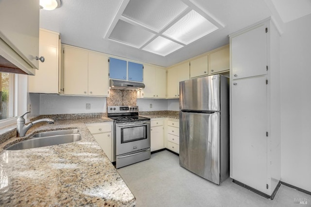 kitchen featuring light stone counters, sink, stainless steel appliances, and cream cabinetry