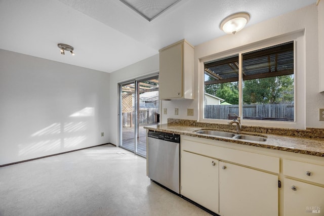 kitchen featuring cream cabinets, stone countertops, stainless steel dishwasher, and sink