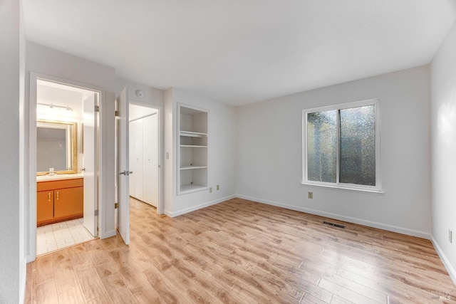 spare room with light hardwood / wood-style flooring, built in features, and sink