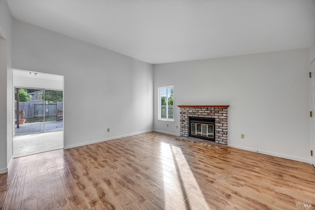 unfurnished living room with light wood-type flooring and a brick fireplace