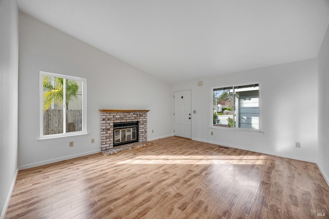 unfurnished living room featuring high vaulted ceiling, light hardwood / wood-style floors, and a brick fireplace