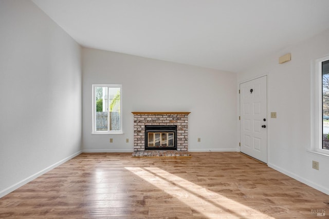 unfurnished living room with light hardwood / wood-style floors, lofted ceiling, and a brick fireplace