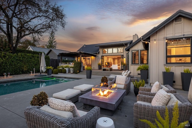 back house at dusk featuring a fenced in pool, an outdoor fire pit, and a patio area